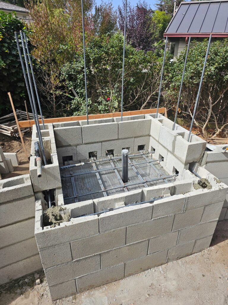 Concrete block foundation with steel reinforcement visible during masonry construction and structural work.