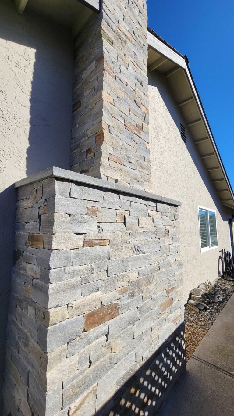 Close-up of coursed natural stone veneer with varied earth tones showing how to match new stonework to existing stone.